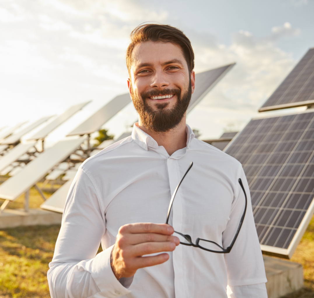A man standing in front of solar panels smiling.